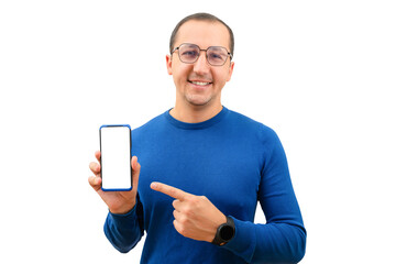 Young man in glasses looking at camera pointing finger at mobile phone isolated on white background