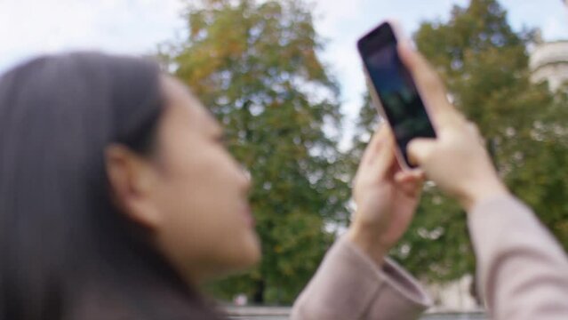 Attractive young female using her phone to take pictures outside in the city, in slow motion 