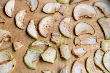 Sliced apple slices are laid out on a cutting board and dried in the kitchen. Dried apples