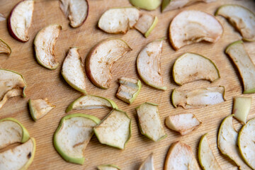 Sliced apple slices are laid out on a cutting board and dried in the kitchen. Dried apples