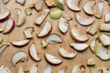 Sliced apple slices are laid out on a cutting board and dried in the kitchen. Dried apples