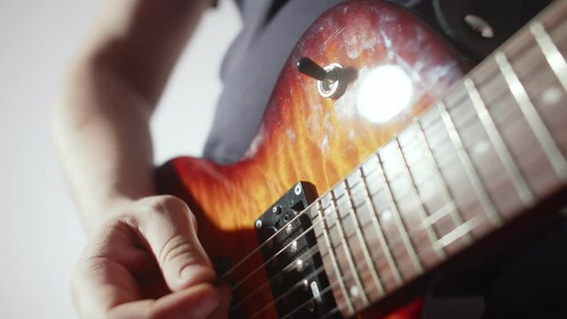 Musician plays strings of an electric guitar and switches toggle switch, closeup hands. Musician in studio plays an electric guitar, switches toggle switch. Concept music and technology