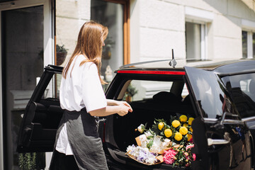 Florist placing flowers in car. Flower delivery concept.