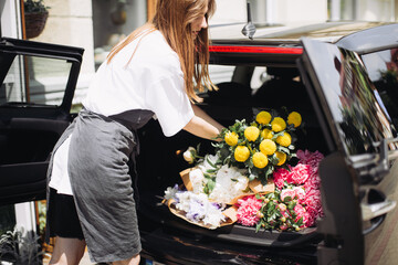 Florist placing flowers in car. Flower delivery concept.