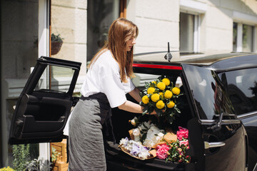 Florist placing flowers in car. Flower delivery concept.