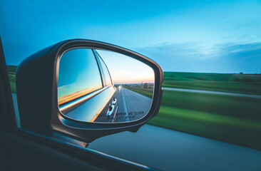 Side mirror of a car looking back - obrazy, fototapety, plakaty