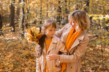 Beautiful lifestyle autumn photo mother and child walks evening in the park, warm sunlight.