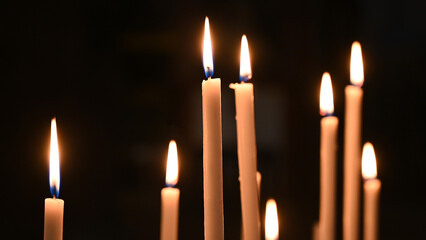Candles burning in cathedral. Votive candles glows in the church. Prayer lighted candles in a...