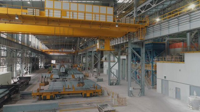 Yellow overhead crane in a modern factory. The work of an overhead crane at a factory. Working process at a metal production factory. Crane work at the factory.