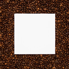 White square card on brown roasted coffee beans. Minimal concept of copy space.