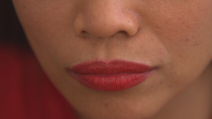 CLOSE UP: Detailed shot of young female lips after applying shiny red lip gloss