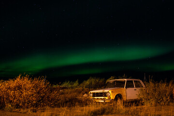 Fototapeta na wymiar old abandoned car against the backdrop of the northern lights