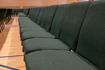 selective focus on a padded seat cushion of a row of chairs in a auditorium. 