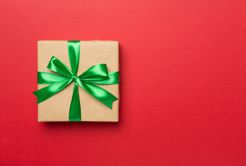 Gift box with green ribbon bow on color background, top view