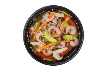 Instant soup, noodles wok, with vegetables, herbs and sesame. In a black round plate. On a white background.