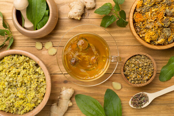 Herbal tea with ingredients on wooden background, top view
