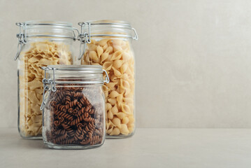 Three different types of pasta in glass jars.