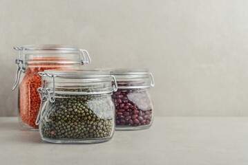 Raw mung beans, red lentils and  red beans in glass jars.
