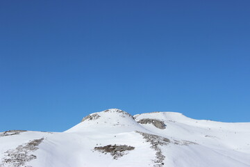 Fototapeta premium Beautiful landscape of mountains covered with white snow and clear blue sky in the background 