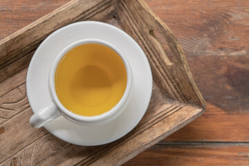 green herbal tea in a white cup with a saucer on a wooden table in a green autumn garden on a sunny day