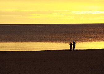 Fototapeta na wymiar a young couple on the shore looks towards the sunset, a beautiful romantic sunset photo
