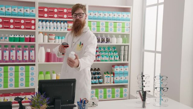 Young redhead man pharmacist scanning pills bottle using computer at pharmacy