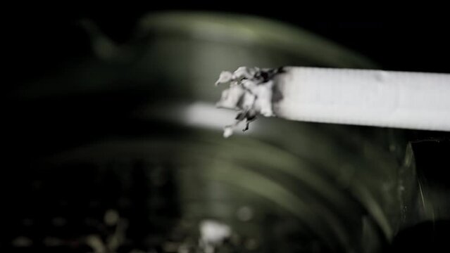 Lit cigarette burning in ashtray macro shot. High quality 4k footage