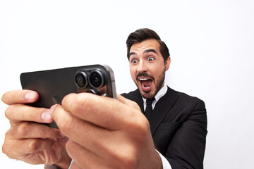 A male businessman gamer plays games on his phone and smiles happily with his teeth. Trading and winning at casinos online via phone. Close-up wide angle photo