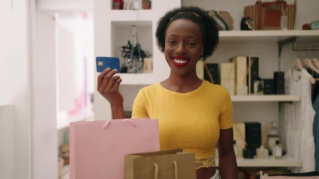 African american woman shop assistant holding credit card at clothing store