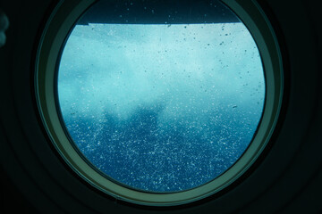 Bubbles visible through the porthole of a submarine surfacing in front of Waikiki Beach in...