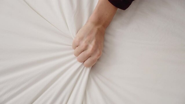 Young beautiful hispanic woman holding bedsheet at bedroom
