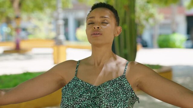 African american woman breathing with arms open at park