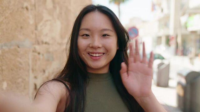 Young chinese woman smiling confident having video call at street