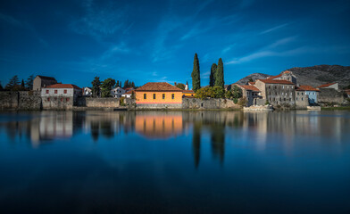 Trebinje view with beautiful reflection of old tonw on water and blue sky with white clouds and stone bridge