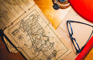 old map and books with glasses above a table planning a trip to portugal