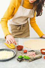Caucasian teenage girl in an apron prepares pizza.