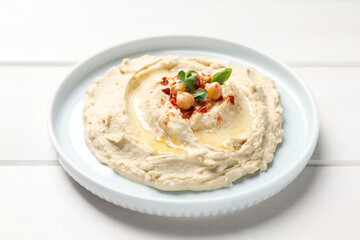Tasty hummus with garnish on white wooden table