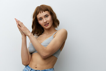 Obraz premium a beautiful, sexy, woman with tanned skin color and red hair, a toned body, stands on a white background holding her hands in a gentle gesture and smiles pleasantly