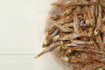 Tasty dried anchovies on white wooden table, top view. Space for text