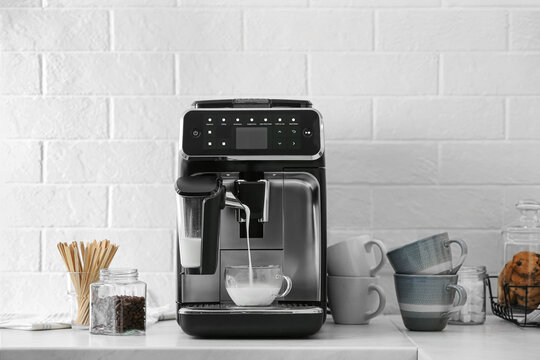 Modern Coffee Machine Pouring Milk Into Glass Cup On White Countertop In Kitchen