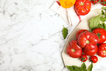 Fototapeta na wymiar Flat lay composition with different ripe tomatoes and leaves on white marble table. Space for text