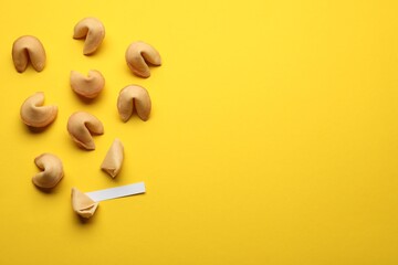 Many tasty fortune cookies with predictions on yellow background, flat lay. Space for text