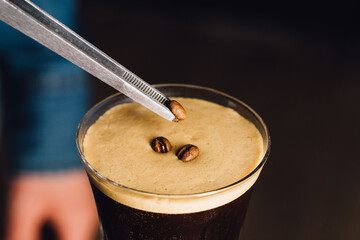 close up garnishing an espresso martini cocktail with coffee beans