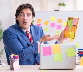 Young male handsome employee in conflicting priorities concept