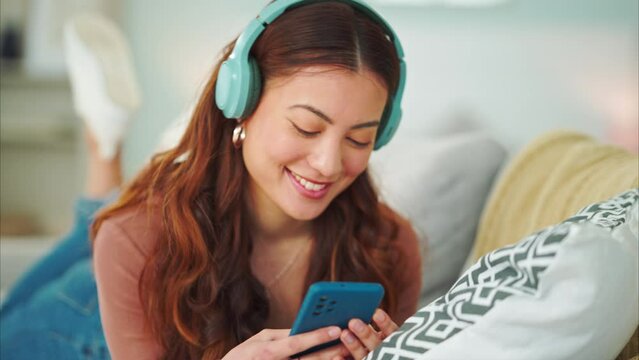 Girl, phone and music on sofa to relax with headphones with smile, typing and happy on social media. Woman, smartphone and streaming song on internet while reading communication, blog post or email
