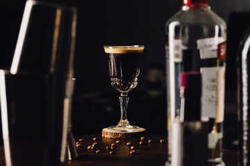 espresso martini cocktail in a fancy elegant glass behind bottles with coffee beans in a table