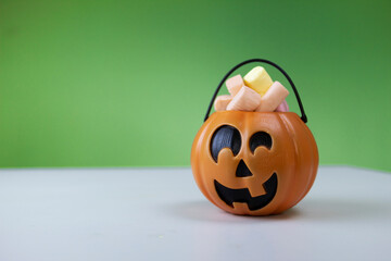 Halloween, pumpkin party decoration, pumpkin with candy inside. Front view with green and white background.Smiling Halloween pumpkin for kids. jack o lantern