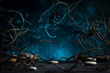 Halloween scary dark blue background with twisted branches, bats, stones and spiders, copy space