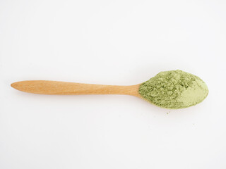 Wheatgrass powder in wooden spoon on white background. Herbal medicine. Closeup photo, blurred.