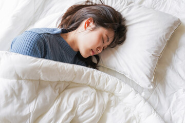 布団に入って睡眠を取る若い女性